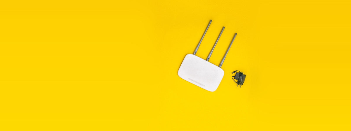 Router wifi blanco con antenas sobre fondo amarillo